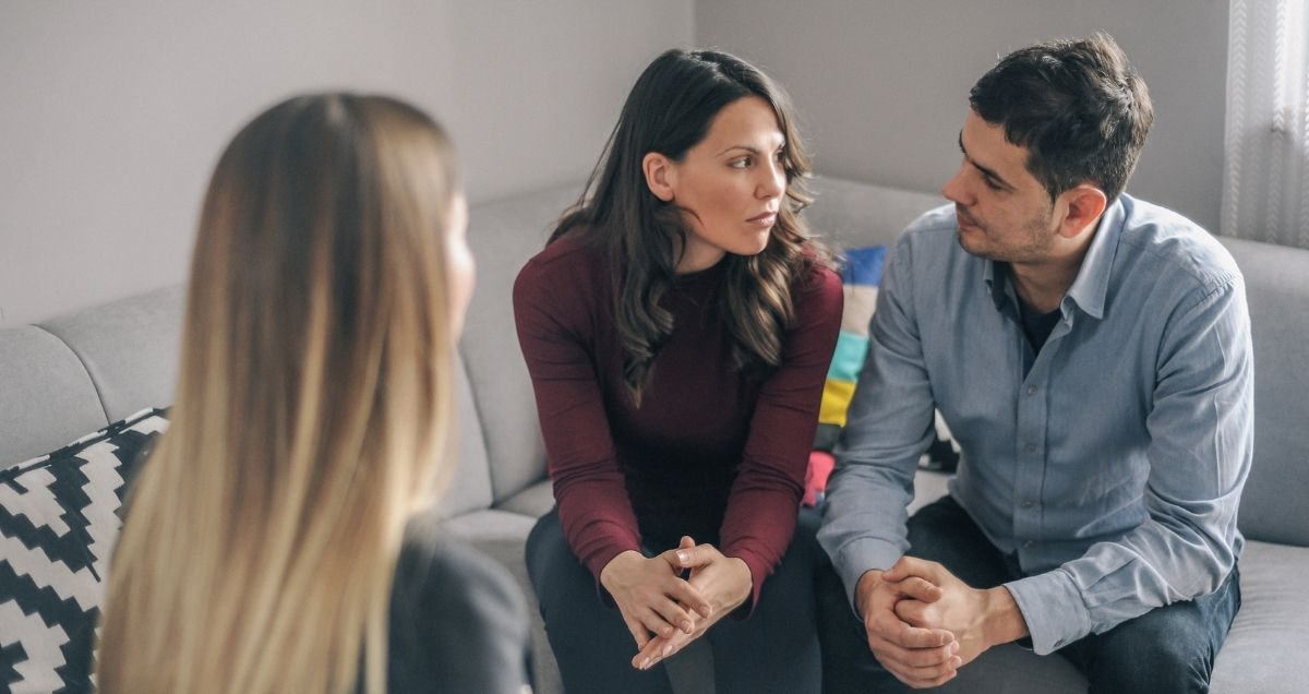 A tense marriage counseling session with a husband, wife, and therapist.