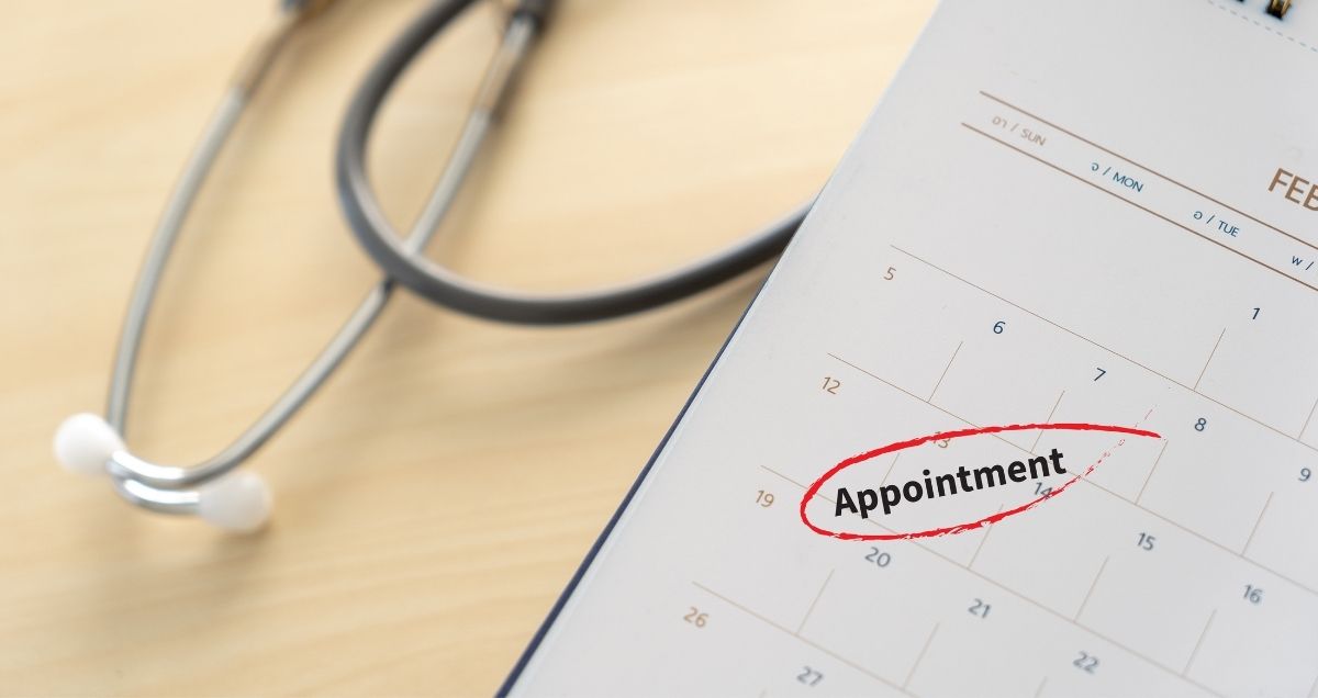 A closeup of a stethoscope and a calendar with the word "appointment" circled on it in red.