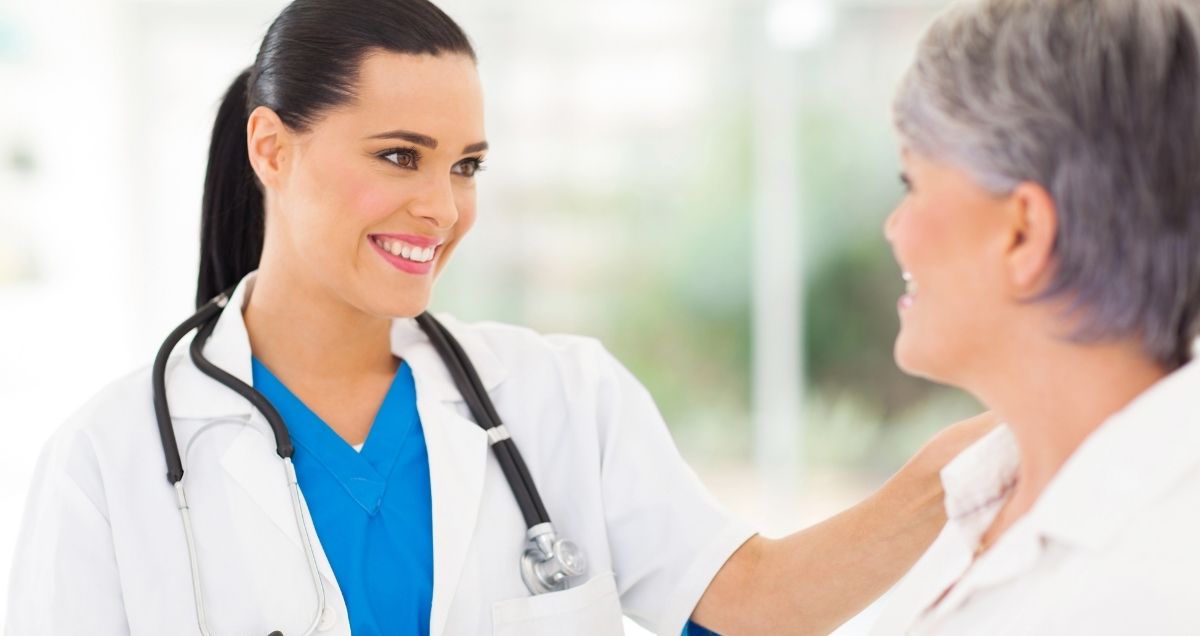 A caring and compassionate female doctor with her hand on a patient's shoulder.