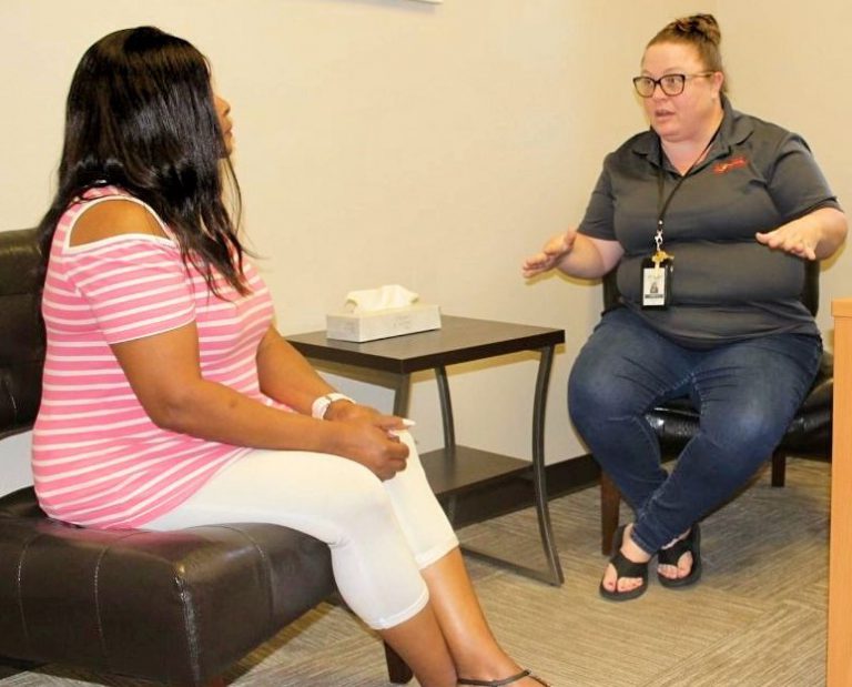 A therapist counseling her patient in behavioral health as they both sit in an office with a tissue box.