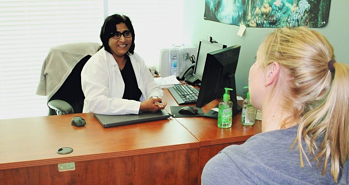 A Psychiatric-Mental Health Nurse Practitioner consulting and helping a patient at her desk.