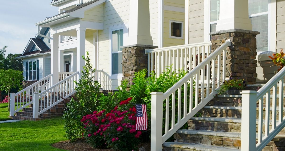 New and colorful townhomes with stairs leading to the front porch in a beautiful suburban neighborhood with front lawns.